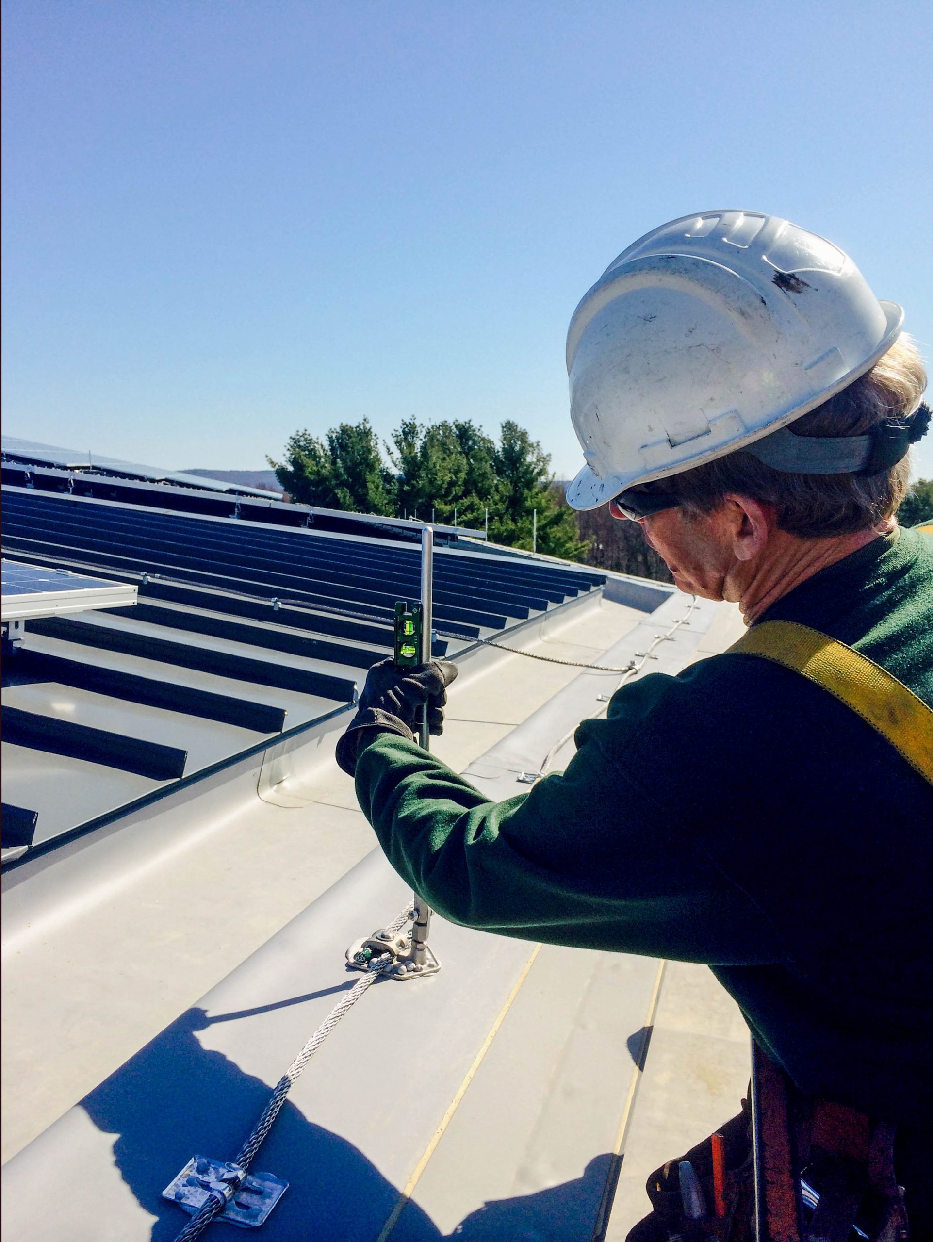 Lightning protection technician installing conductor on roof